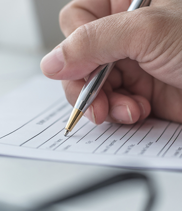 Una mano con una lapicera escribiendo en un papel
